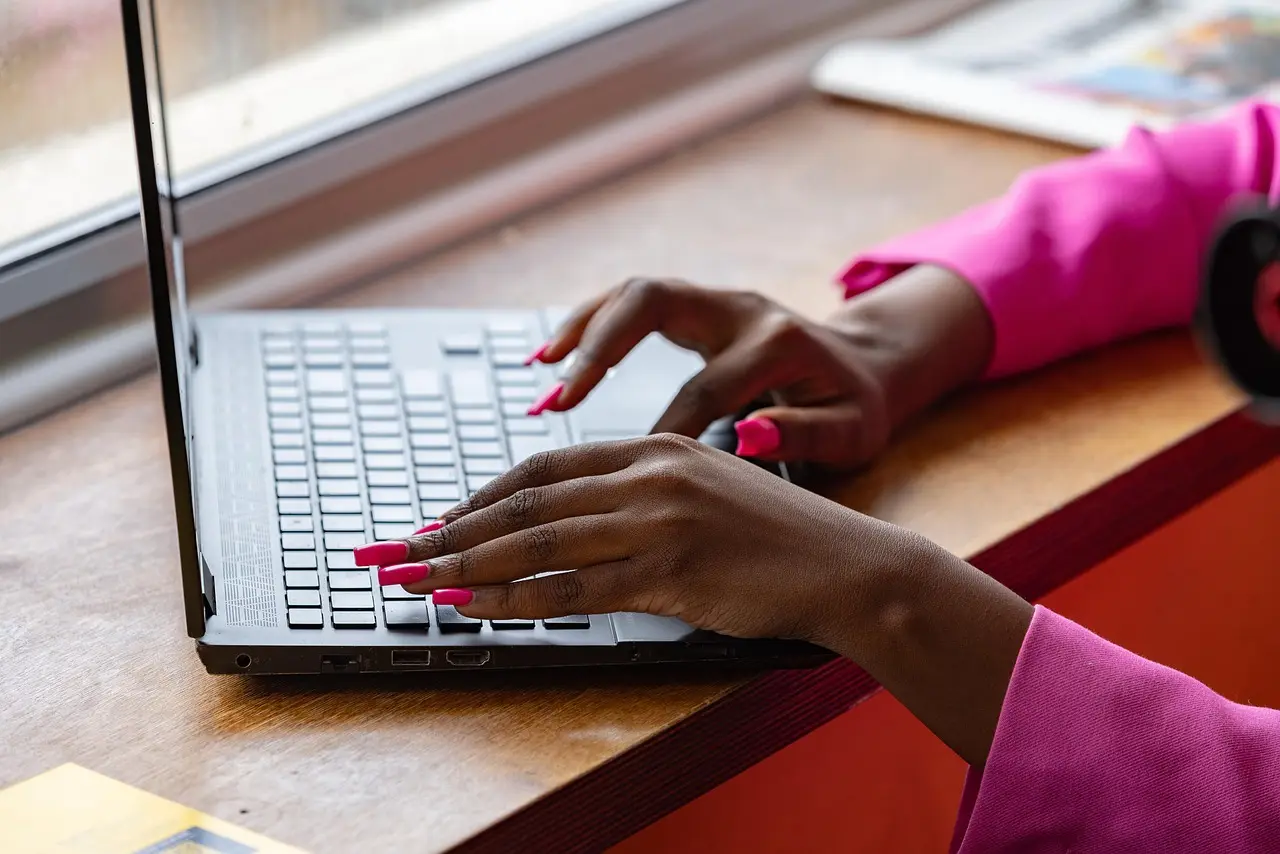 Hands typing on a laptop at a small office desk